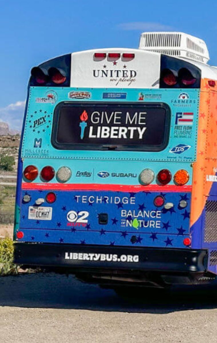 libbus sponsors exterior of united we pledge liberty bus in desert next ro american flag